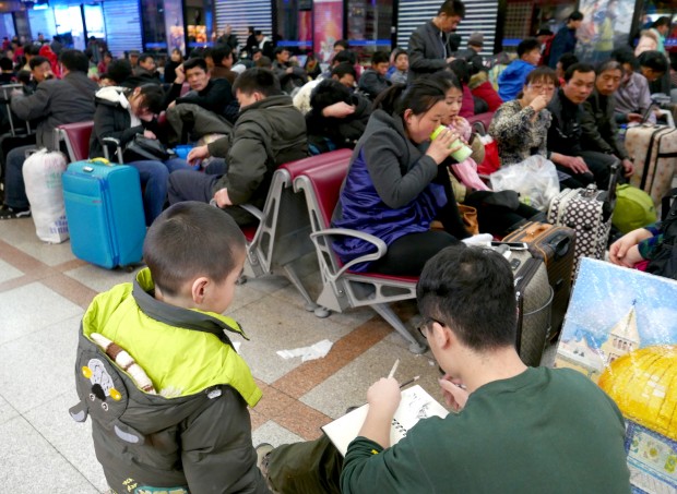 Jovem chinês desenha em um dos salões de embarque de uma estação de trem em Pequim