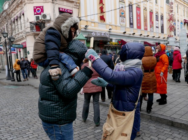 Mãe oferece sorvete para a criança no meio de uma rua russa de Harbin